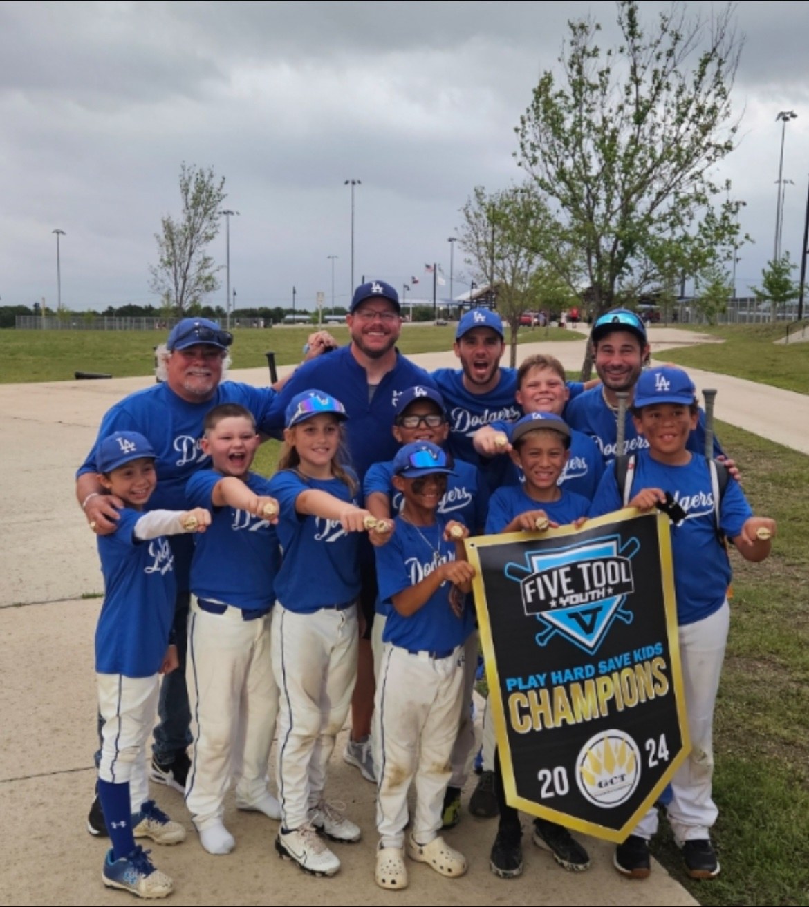 Matt Young and his Dodgers team holding a Five Tool Champions banner and showing their rings