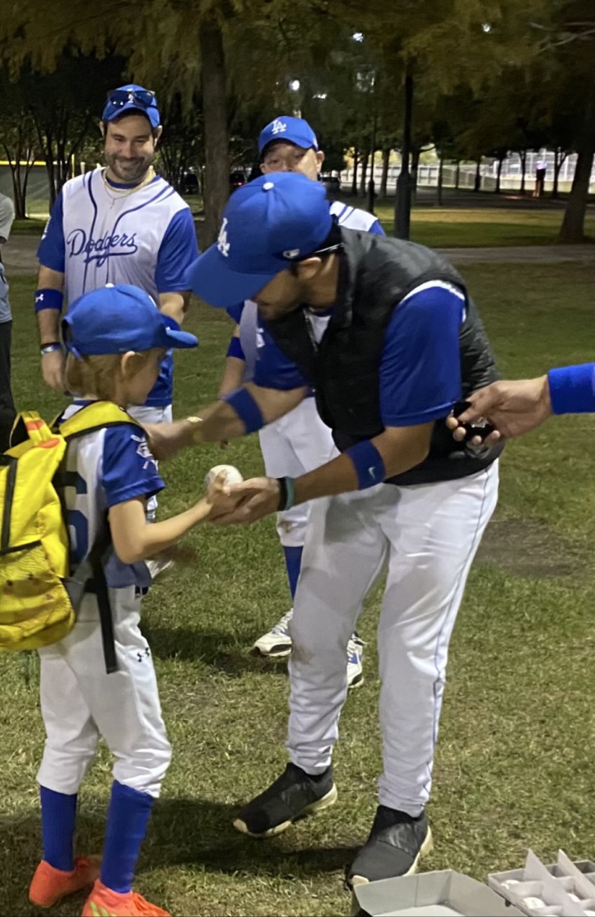 Matt Young presenting a game ball to a young player after a night game