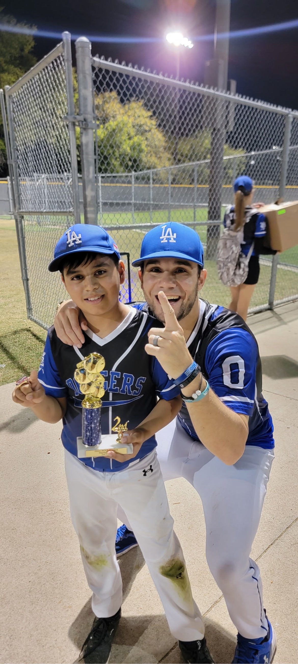Matt Young posing with a young player holding a trophy and showing a championship ring