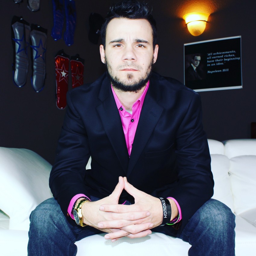 Matt Young in a suit and pink shirt, seated portrait